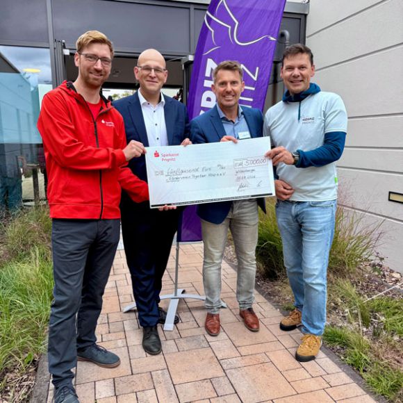 Stefan Plutniok von der Sparkasse Prignitz und Landrat Christian Müller übergeben die Spende von 5000 Euro an Stephan Michelis und Christian Richter. / Foto: LK Prignitz, Gina Werthe